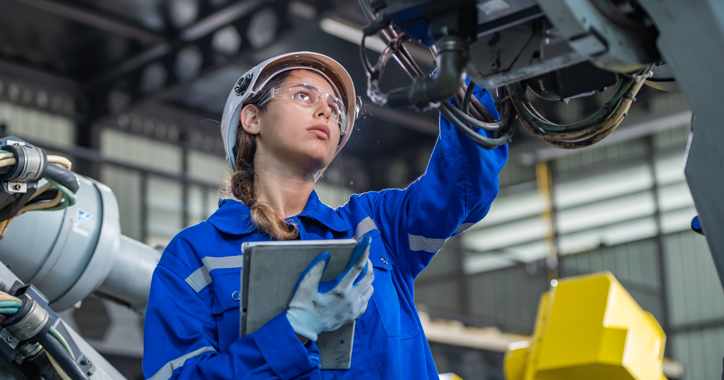 A young female engineer checks a machine.
