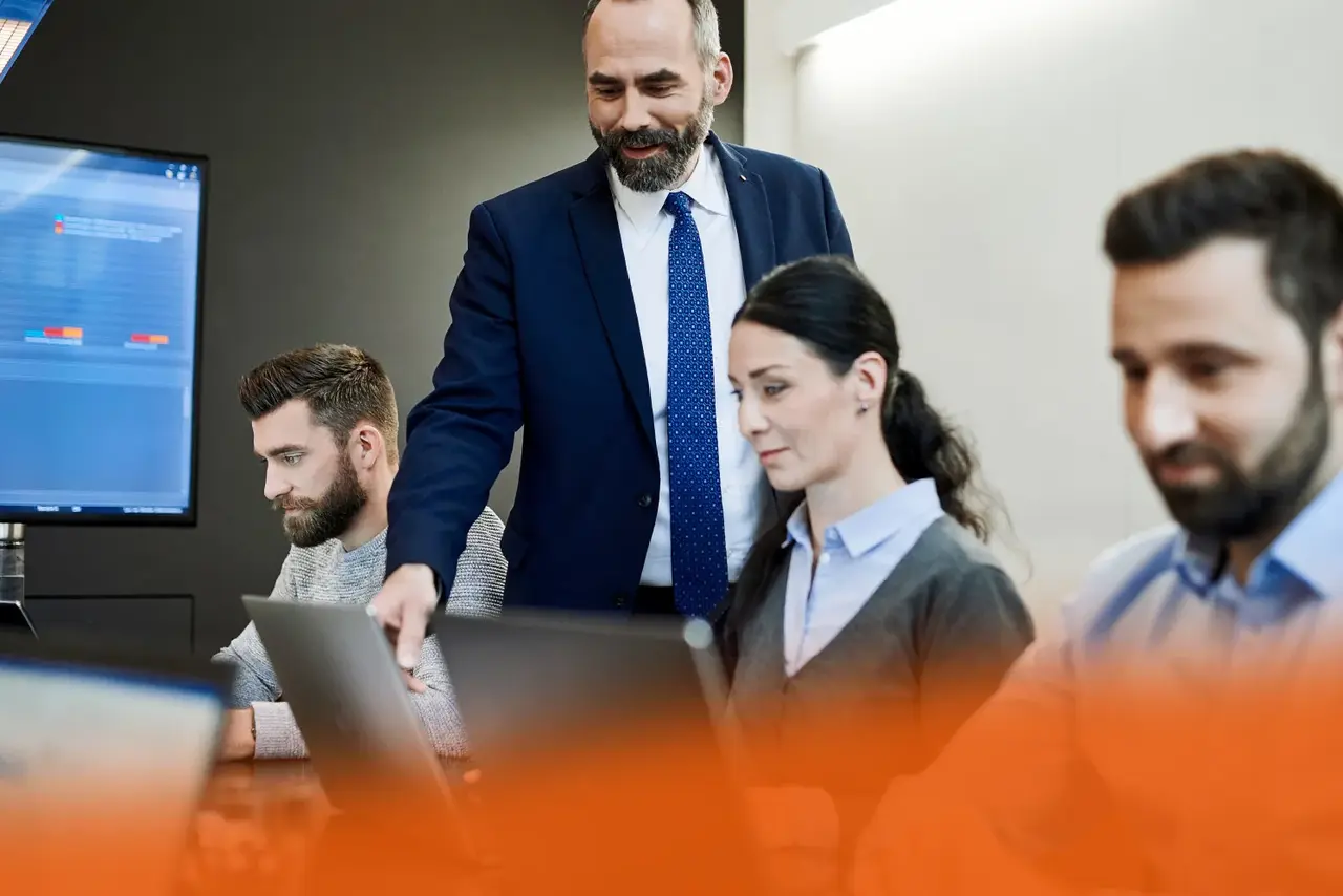 IMS-Software von Babtec Mehrere Personen sitzen in einem Besprechungsraum und arbeiten am Laptop