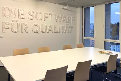 Meetingraum Meetingraum mit Schriftzug "Die Software für Qualität" an der Wand