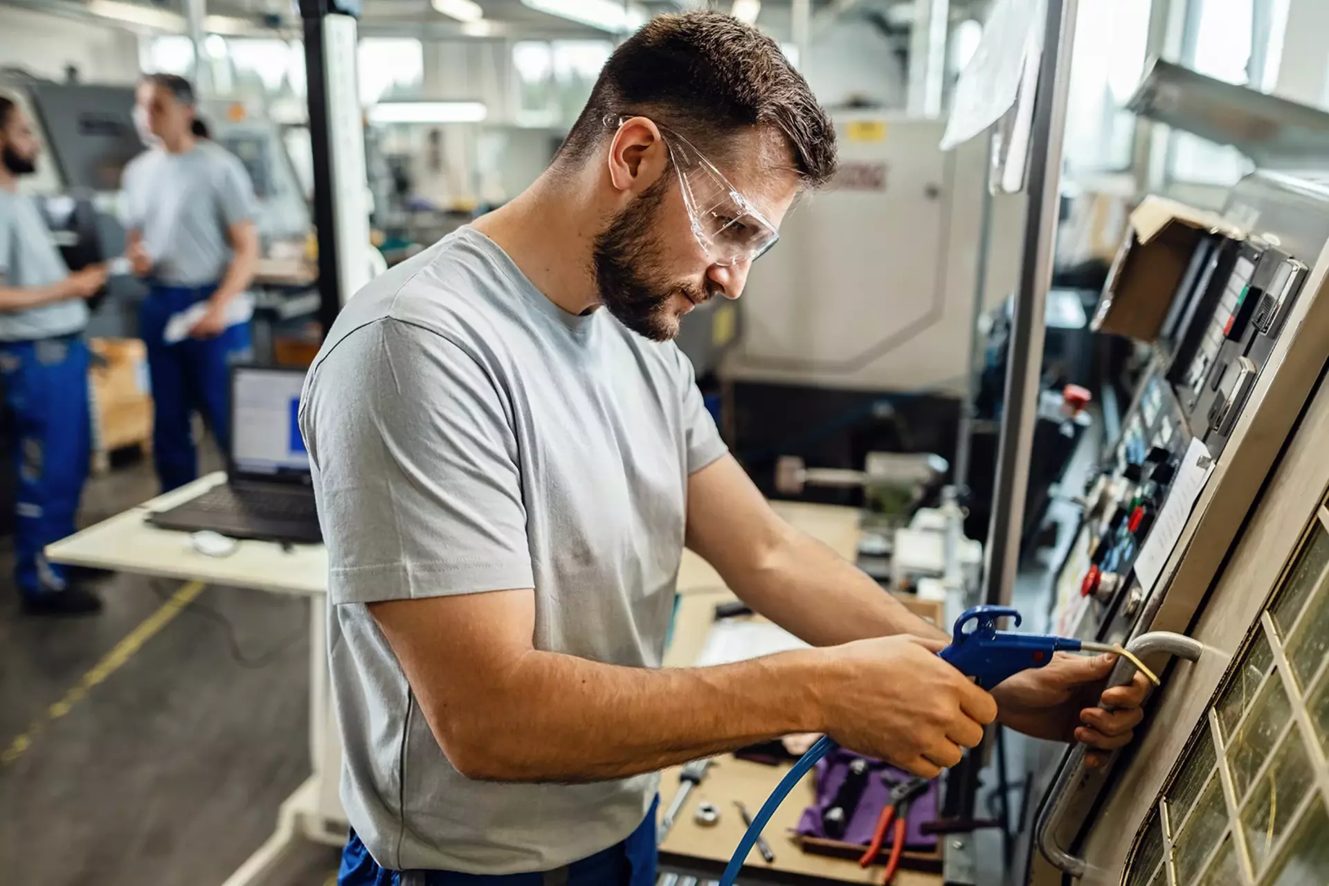 Qualitätsprozesse effizient umsetzen QM-Mitarbeiter an einer Maschine in der Produktionshalle