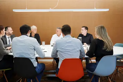 Acht Mitarbeitende sitzen im Meetingraum gemeinsam an einem Tisch