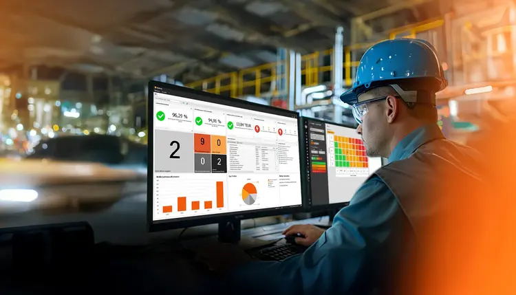 Integrierte QM-Software In einem Produktionsbetrieb schaut ein Mann auf zwei Bildschirme, auf dem QM-Software von Babtec zu sehen ist
