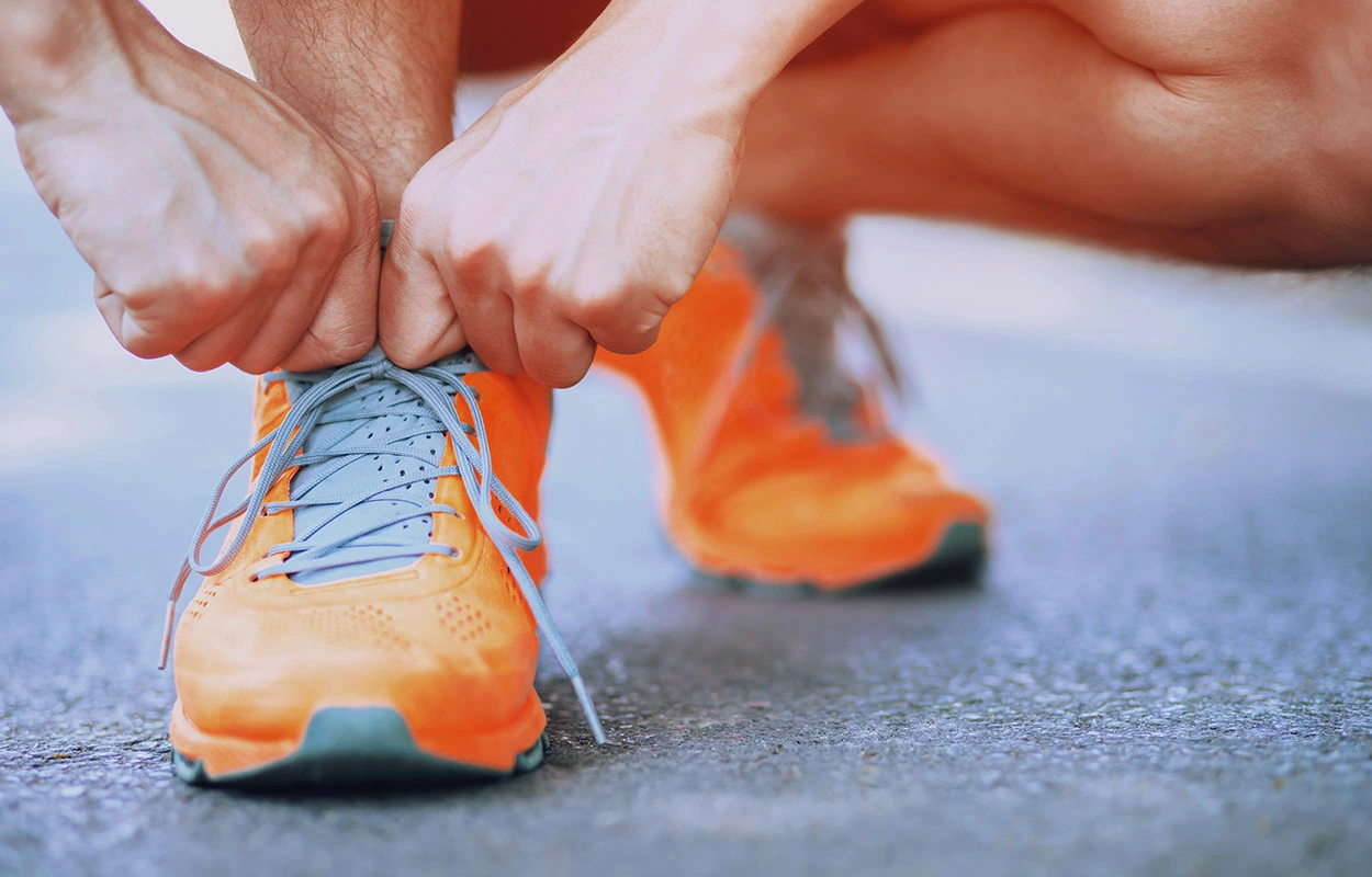 Mann macht sich mit seinen orangefarbenen Sportschuhen bereit für den Run.