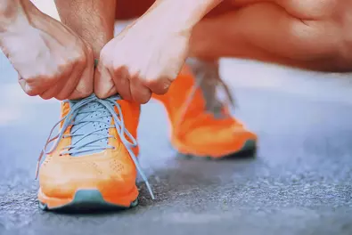 Impulsabend rund um das Thema Eigenmotivation Mann macht sich mit seinen orangefarbenen Sportschuhen bereit für den Run.