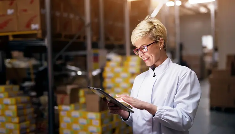 Eine lächelnde Frau arbeitet in einem Unternehmen am Tablet