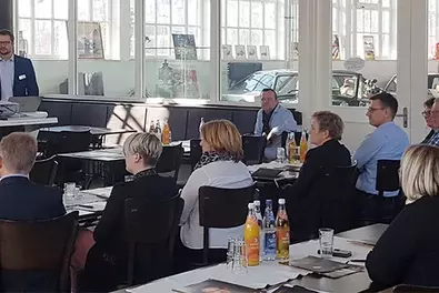Teilnehmer des Q.Infotag in Nürnberg sitzen gesammelt auf Stühlen