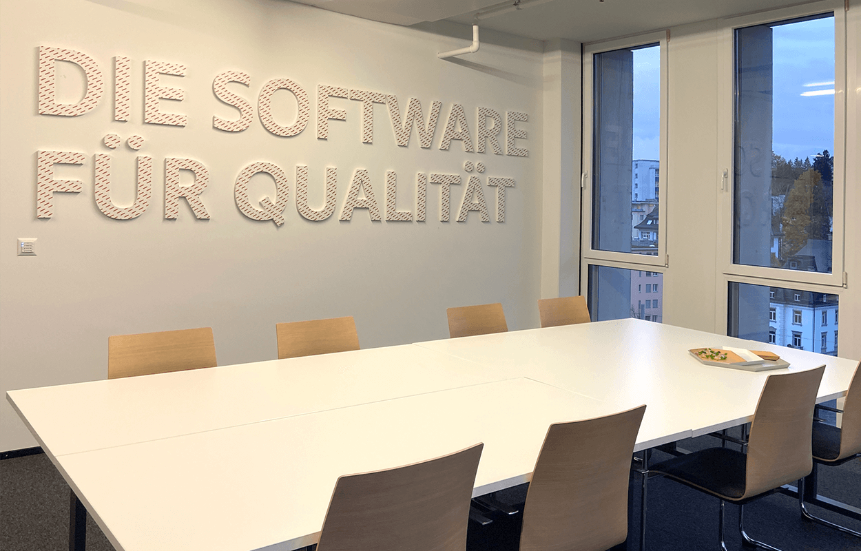 Meetingraum mit Schriftzug "Die Software für Qualität" an der Wand
