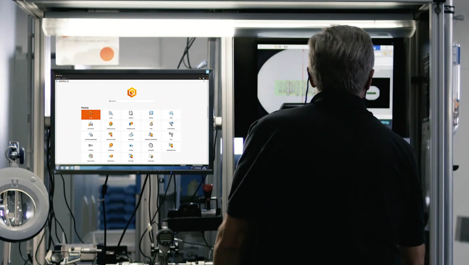Mann neben einem Monitor in einer Produktionshalle, darauf Software BabtecQ